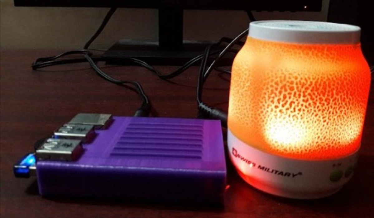 Raspberry Pi in a purple 3D-printed case beside a glowing portable speaker